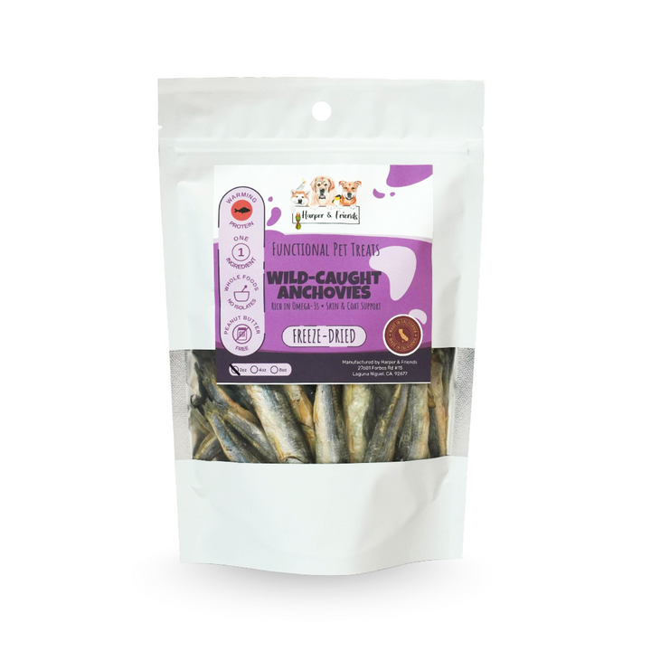 A stand-up pouch of freeze-dried dog treats on a plain white background. The package is white with a purple label panel and a clear window showing the freeze-dried anchovies inside.