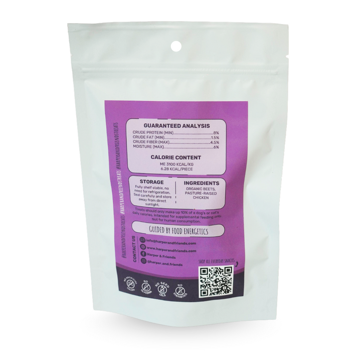 A white stand-up resealable pouch with a large purple back label showing guaranteed analysis, calorie content, storage, ingredients, and a QR code, photographed on a white background.