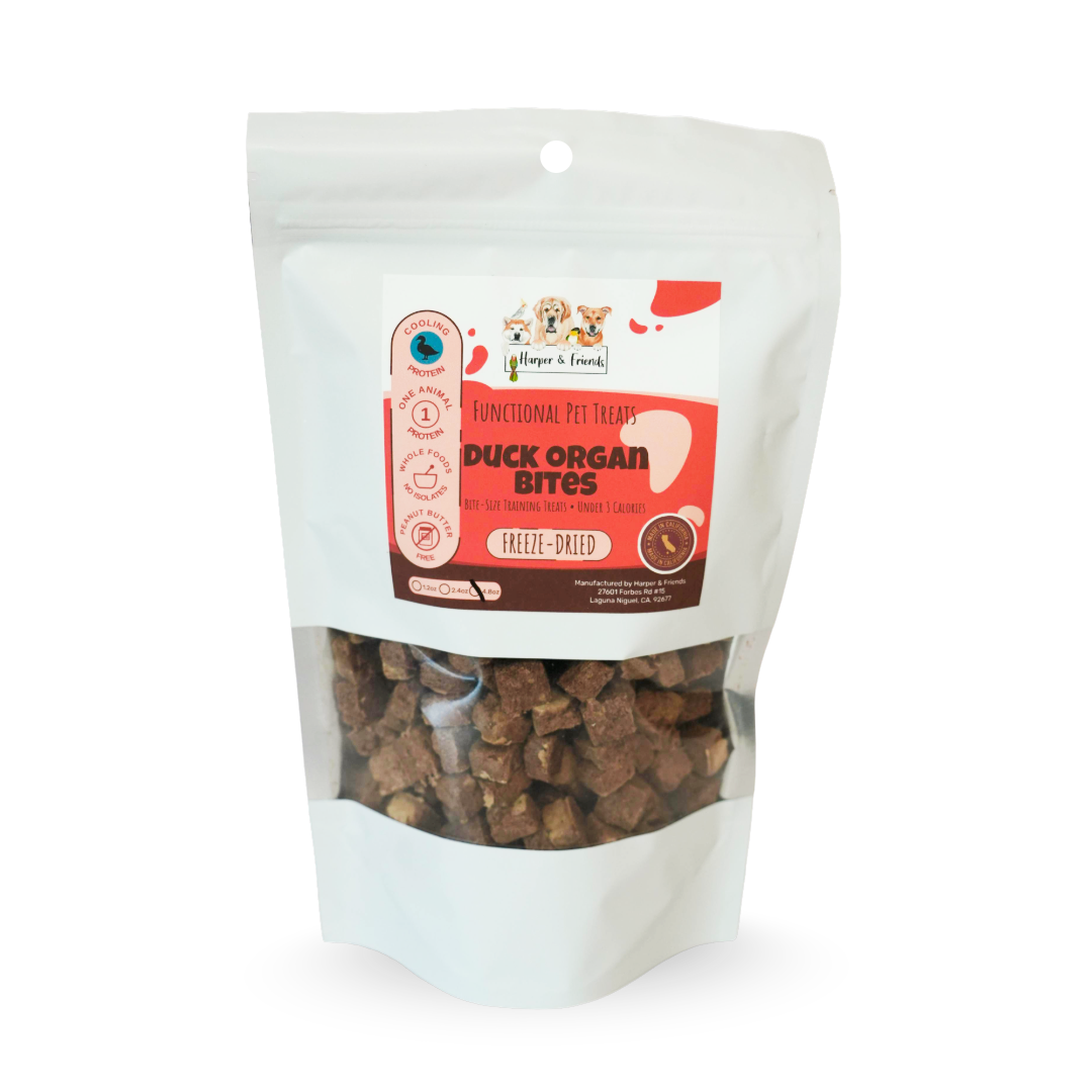 A stand-up pouch of dog treats on a white background. The package is made of white bag with a clear window showing brown duck organ bites treats inside.