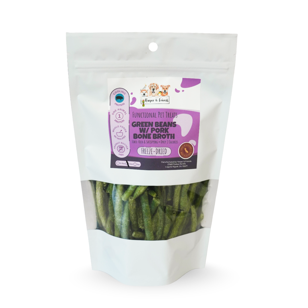 A stand-up pouch of dog treats on a white background. The package is white with a clear window showing green bean with pork bone broth treats inside.