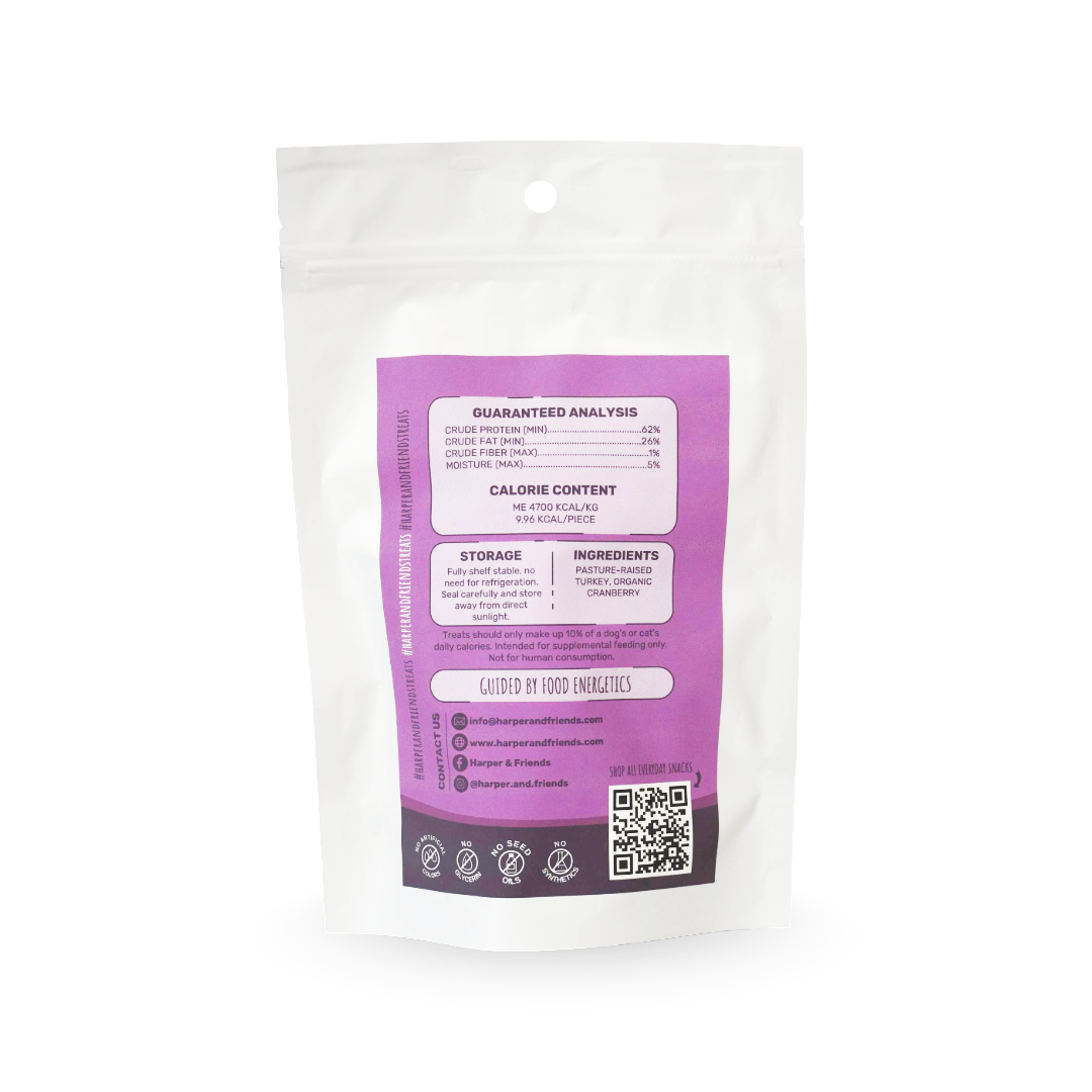 A white stand-up pouch with a large purple and dark purple label showing nutritional information, ingredients, and a QR code, photographed on a clean white background.