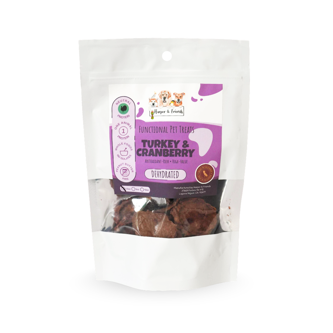 A stand-up pouch of functional pet treats, specifically Turkey &amp; Cranberry treats, with a clear window showing the dark brown treats inside. The packaging features a white and purple label with the brand logo &